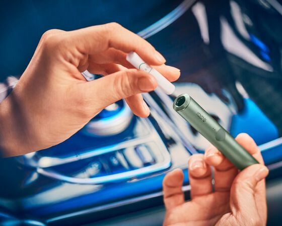 A person inserting an IQOS TEREA stick into an IQOS ILUMA device.