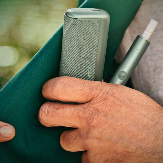 Close up of hand taking IQOS ILUMA device from pocket.
