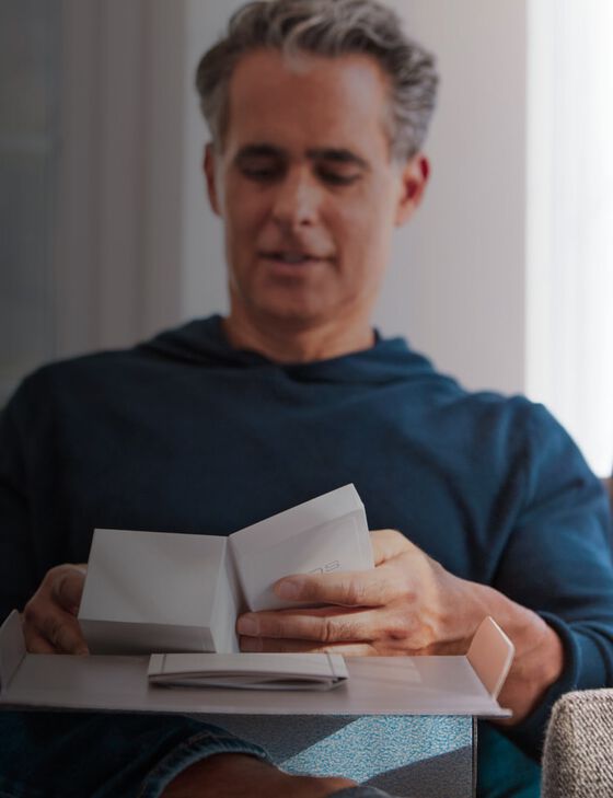 A smiling woman with an IQOS ILUMA device.