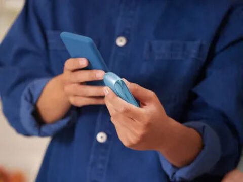 Turquoise IQOS Originals heated tobacco device, held by smiling couple