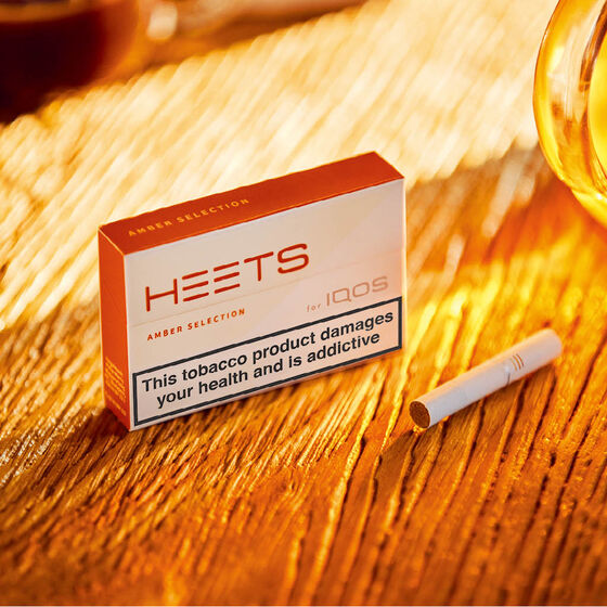 A solid woman in jacket holds IQOS