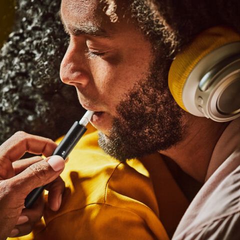 A bearded man using an Obsidian Black IQOS ILUMA PRIME device.