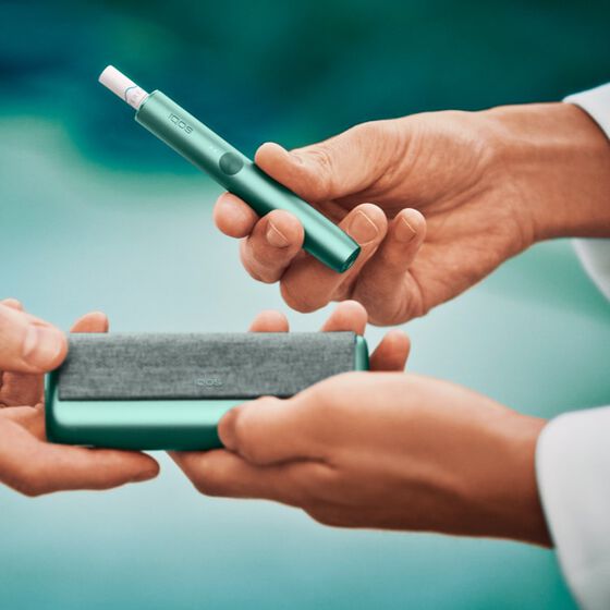 Close up of a chef's hands opening a jade green IQOS ILUMA device.