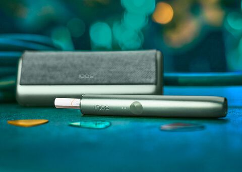 A jade green IQOS ILUMA device and charger.