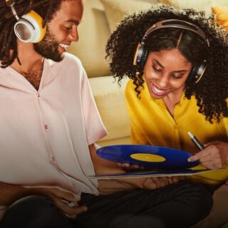 A bearded man wearing headphones holds and IQOS device.