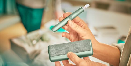 A Jade Green IQOS ILUMA PRIME Holder and Pocket Charger in a person's hands.