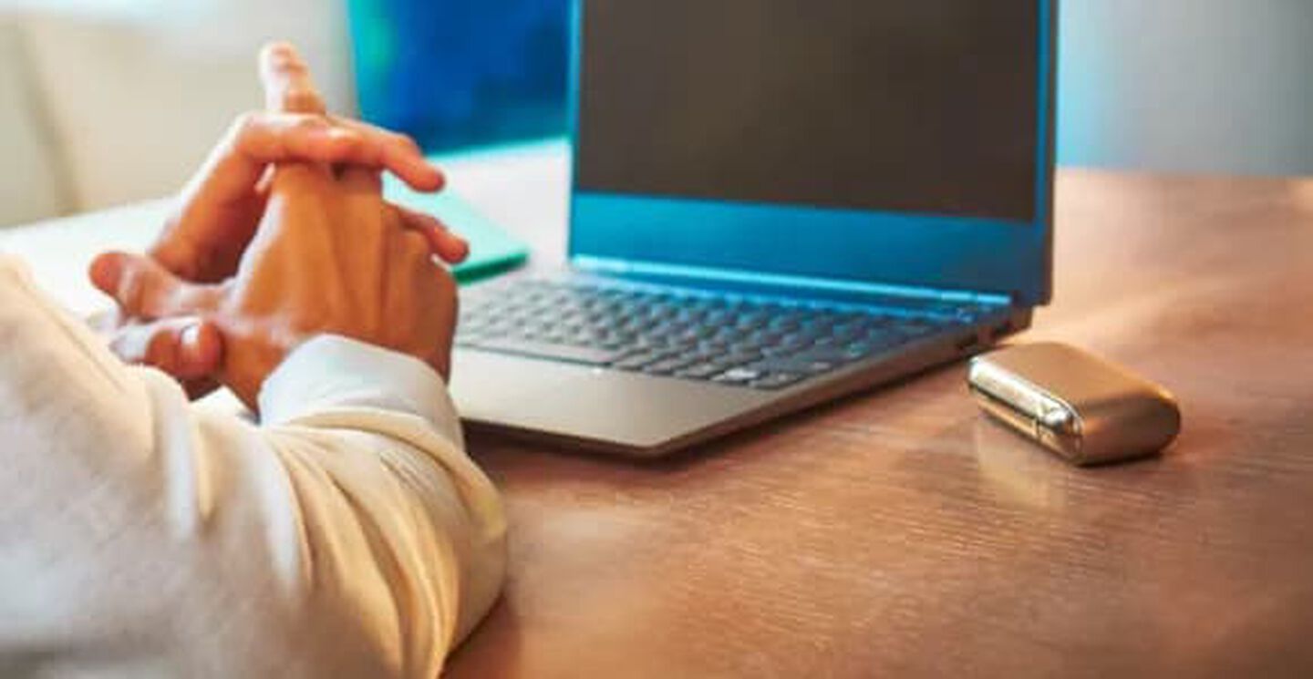 Man using his laptop with his IQOS device on the table
