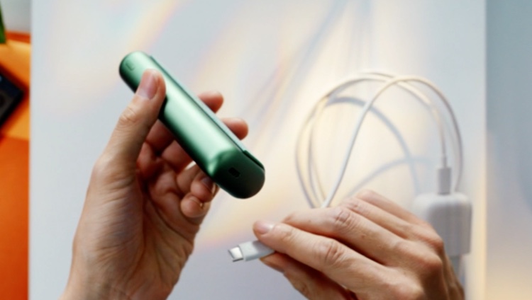 An IQOS ILUMA ONE plugged in with a power adaptor.