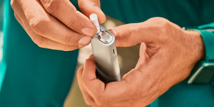 A man holding an IQOS ILUMA ONE device.